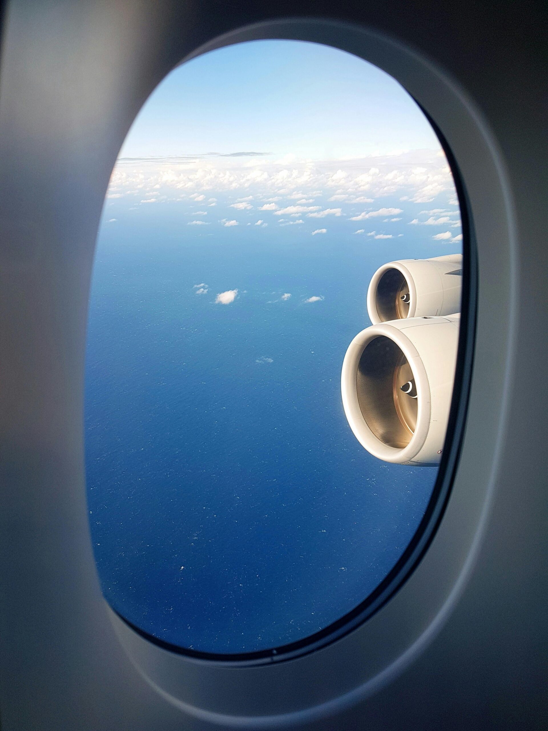 View from airplane window showing the engine and ocean, suggesting travel and adventure.